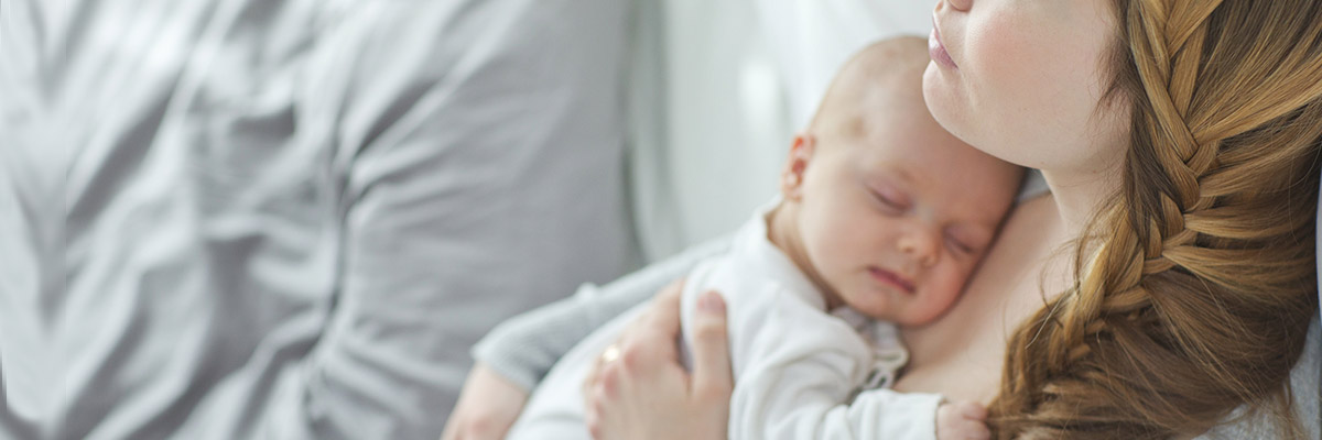 Young woman laying in a hospital bed with newborn baby